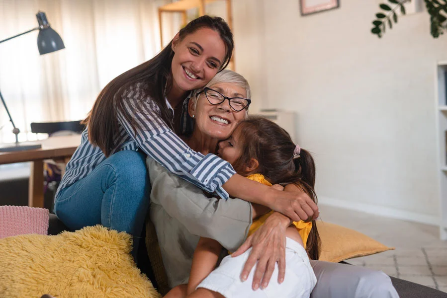 Family portrait of three female generations. Pretty girl hugging her beloved mother and grandmother.